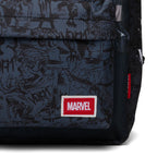 Close-up of a Marvel backpack featuring a dark charcoal and black comic book character pattern, with a red and white embroidered Marvel logo patch on the front pocket.