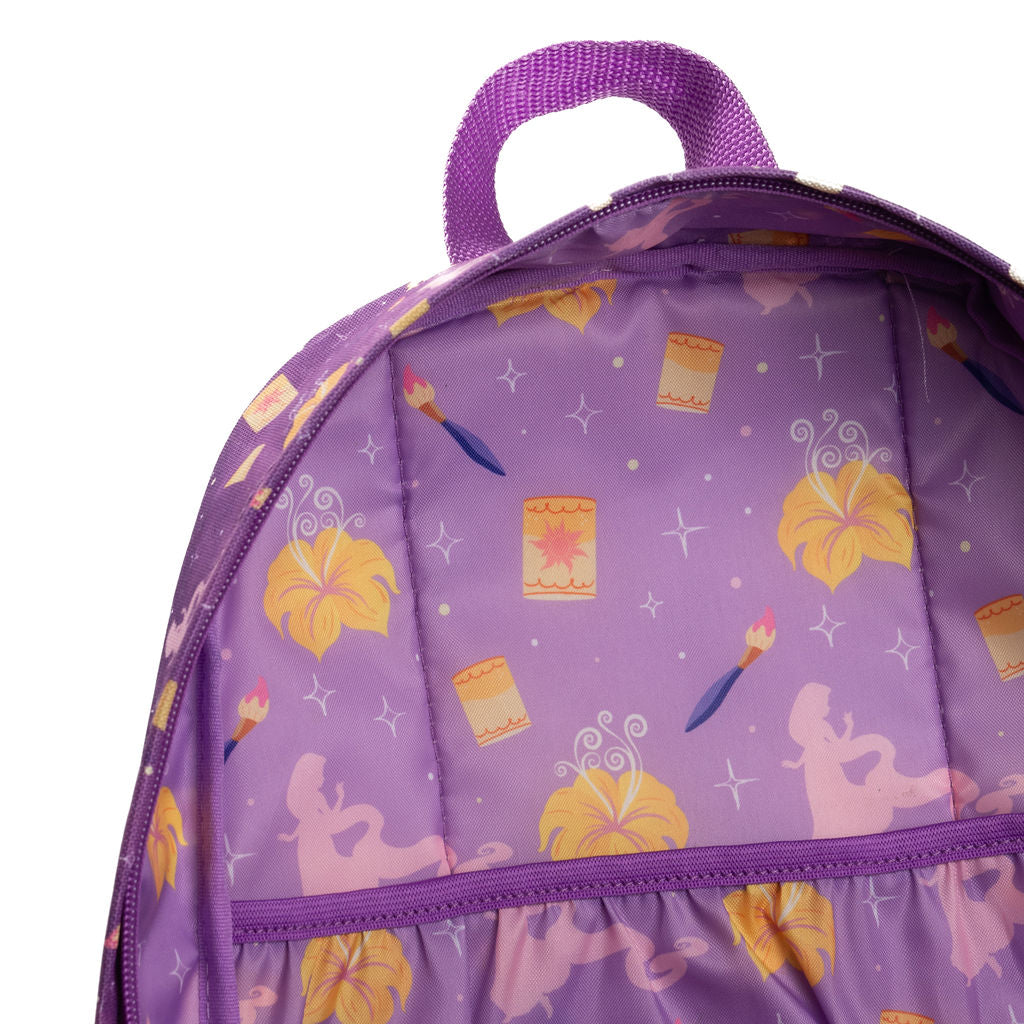 Close-up of a purple backpack interior with a printed pattern of yellow flowers, paintbrushes, paint palettes, and small stars, shown against a white background.