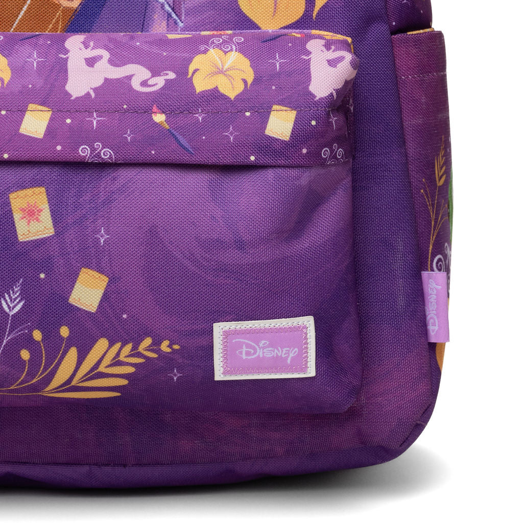 Close-up of a purple Disney backpack featuring a printed pattern with characters, flowers, stars, and leaves, including a visible Disney label on the front pocket.