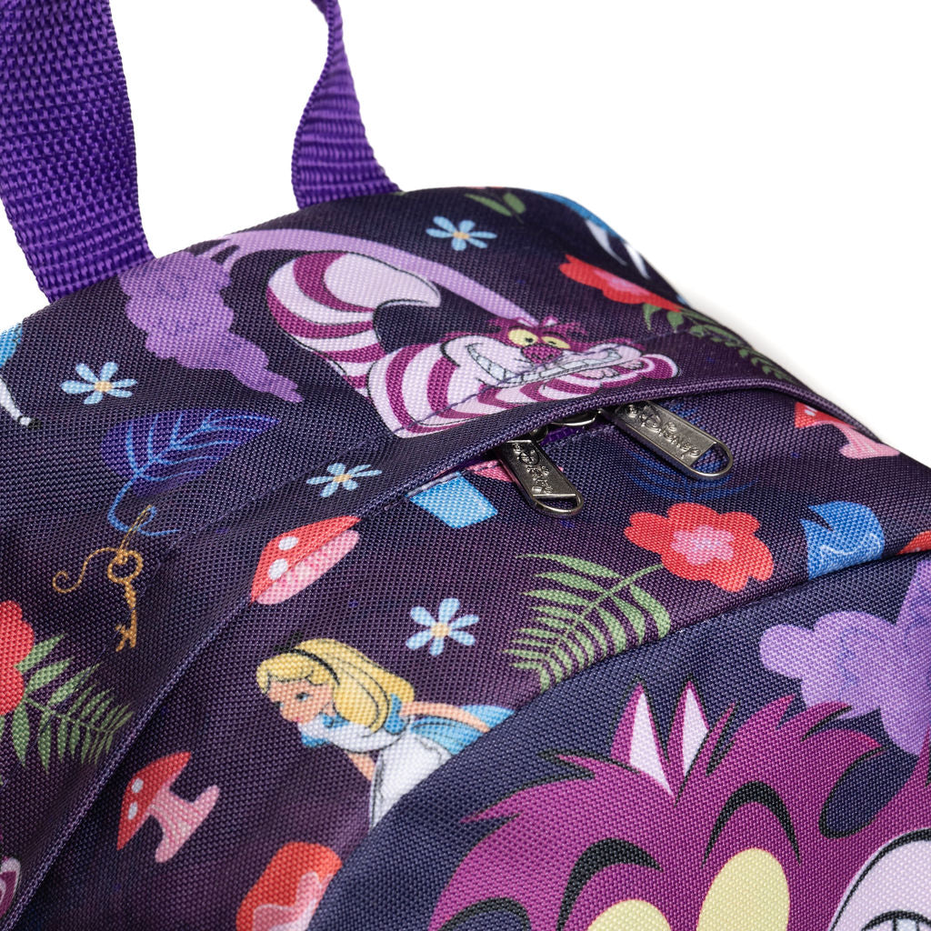 Close-up of a purple backpack featuring a colorful Cheshire Cat and Alice in Wonderland print, with a zippered pocket and purple straps on a white background.