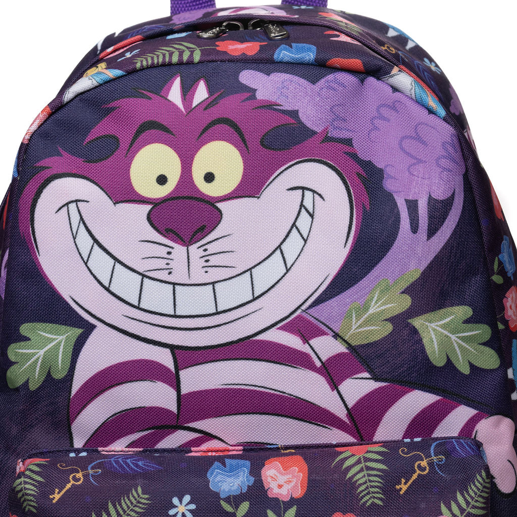 A close up of a kids' backpack featuring a large print of the Cheshire Cat from Alice in Wonderland, green leaves, and a floral pattern on the bottom pocket.