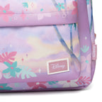 Close-up of a Disney backpack in pastel lavender with a tropical floral and palm tree print, featuring a stitched Disney logo patch on the front.