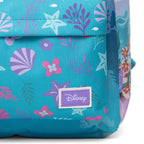 Close-up of a turquoise blue fabric bag with an underwater-themed print featuring purple and pink seashells, starfish, and marine plants. A purple rectangular patch on the front displays the Disney logo.