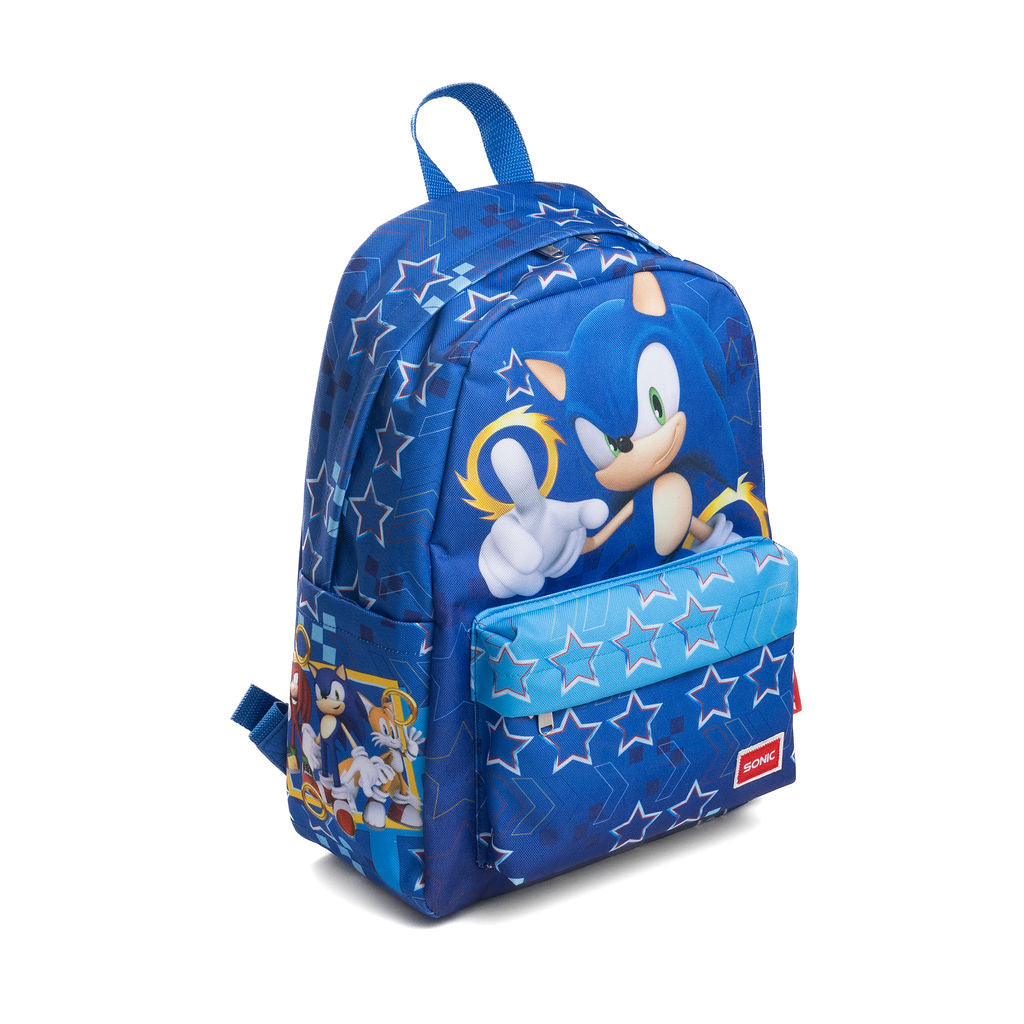 A blue backpack featuring Sonic the Hedgehog graphics, including a large print of Sonic and Tails on the front pocket and a smaller character panel on the side pocket. The backpack has a blue top handle, a front zippered pocket with a blue star-patterned flap, and a red Sonic logo patch on the bottom left corner.
