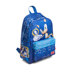 A blue backpack featuring Sonic the Hedgehog graphics, including a large print of Sonic and Tails on the front pocket and a smaller character panel on the side pocket. The backpack has a blue top handle, a front zippered pocket with a blue star-patterned flap, and a red Sonic logo patch on the bottom left corner.