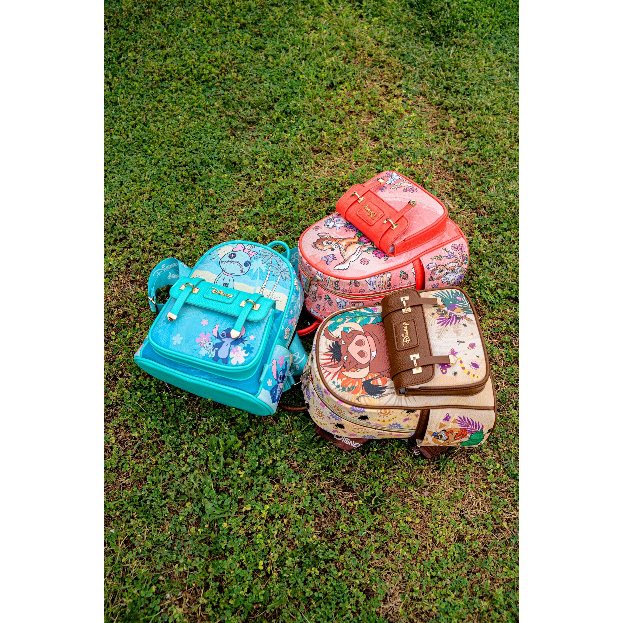 Top-down view of Disney Loungefly mini backpacks featuring Pumbaa, Stitch, and Bambi placed on grass