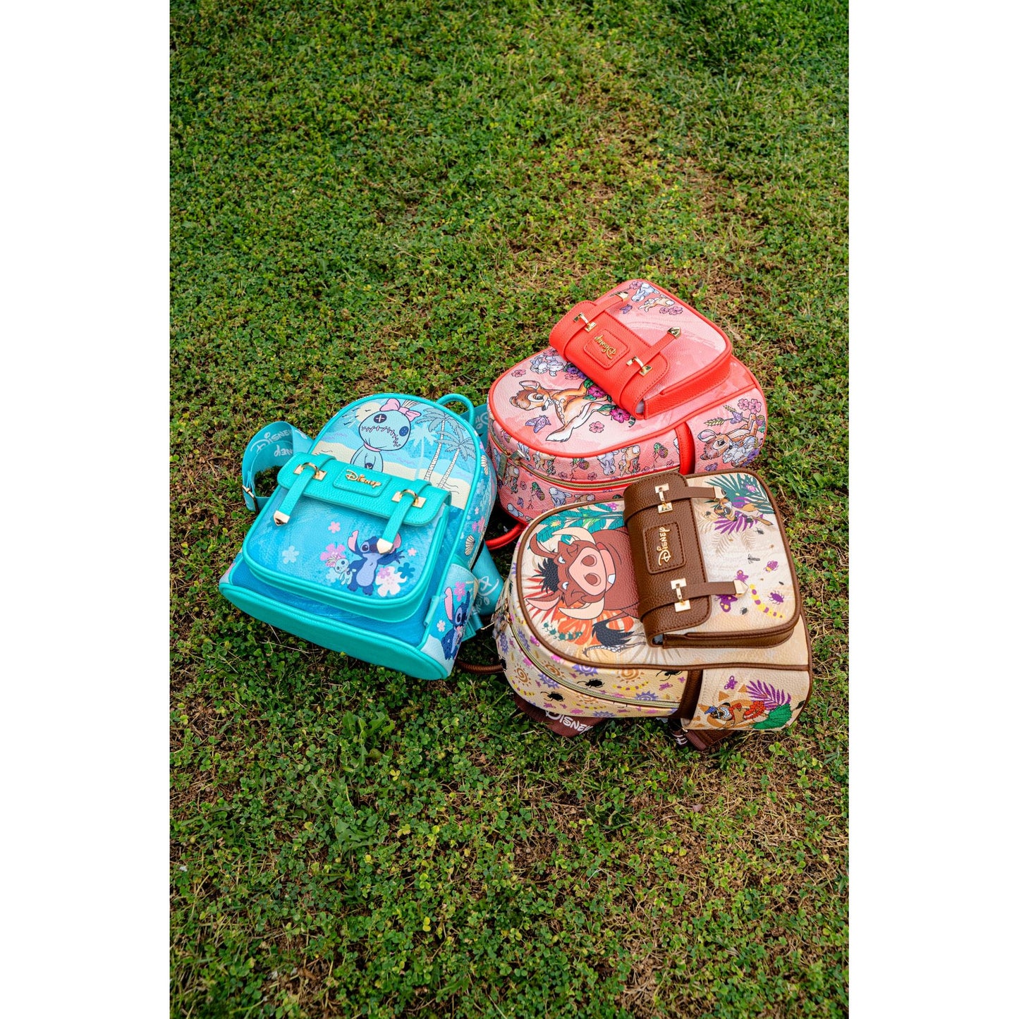 
                  
                    Top-down view of Disney Loungefly mini backpacks featuring Pumbaa, Stitch, and Bambi placed on grass
                  
                