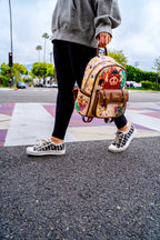 Person crossing the street holding a Disney Loungefly Pumbaa mini backpack from The Lion King collection